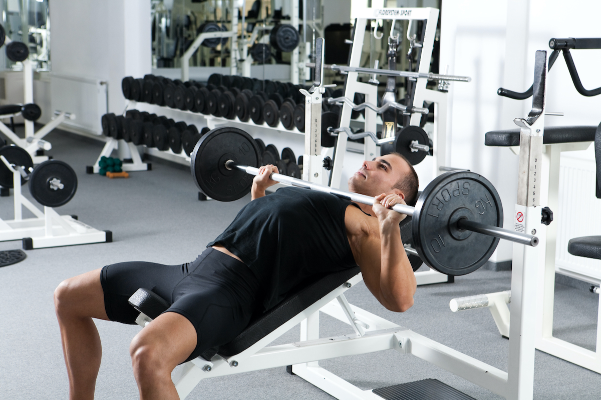 young bodybuilder training in the gym: chest - barbell incline bench press - wide grip