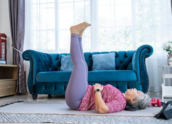 Healthy Senior woman lie on the floor and raise two leg up while doing exercise stretching legs with lying leg lift, workout fitness pose at home