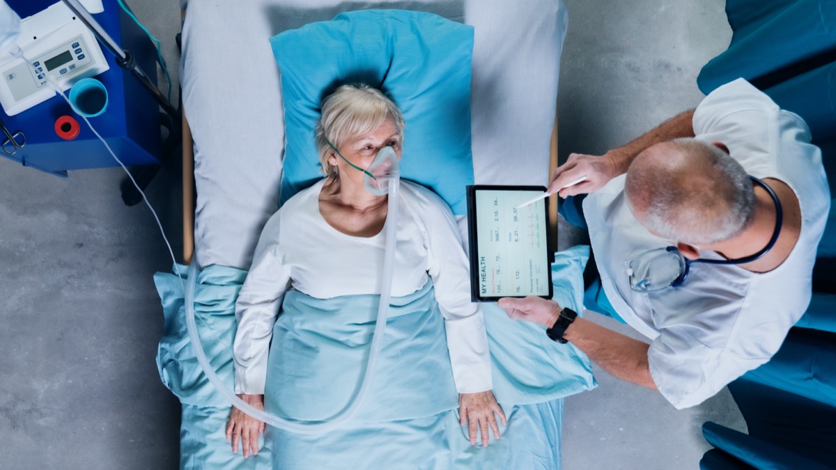 Top view of doctor and covid-19 patient with oxygen mask in bed in hospital, coronavirus concept.