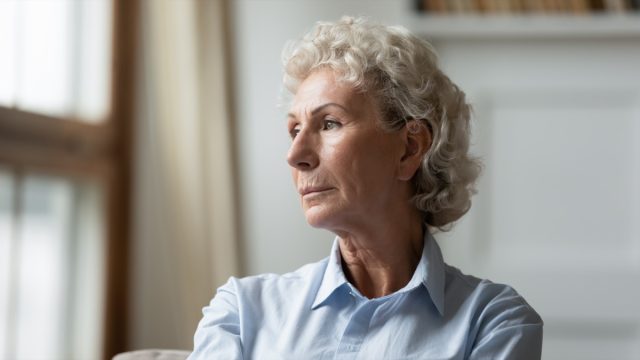 sad senior 70s grandmother look in distance thinking.