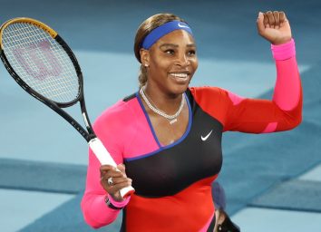 serena williams raising her fist on tennis court while holding racket