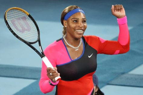 serena williams raising her fist on tennis court while holding racket