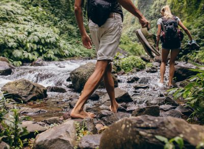 couple-hiking-barefoot-over-stream