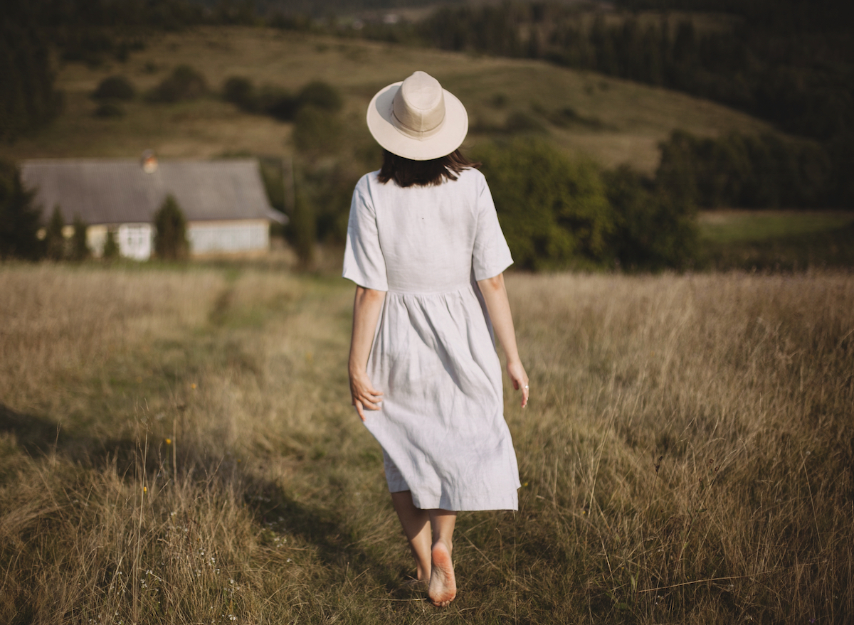 woman-in-white-dress-walking-barefoot-in-field