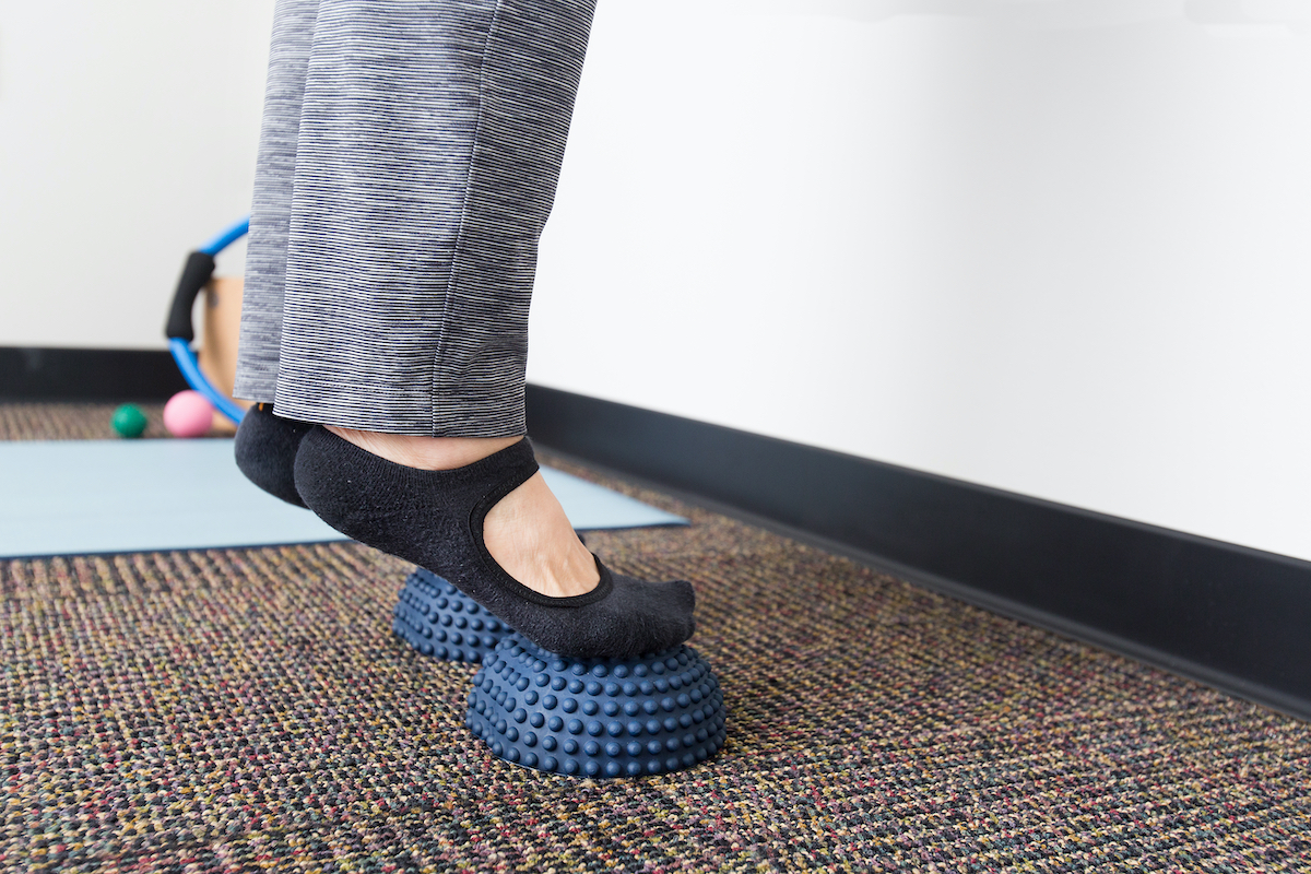 female standing on toes and doing foot stretching exercise in studio