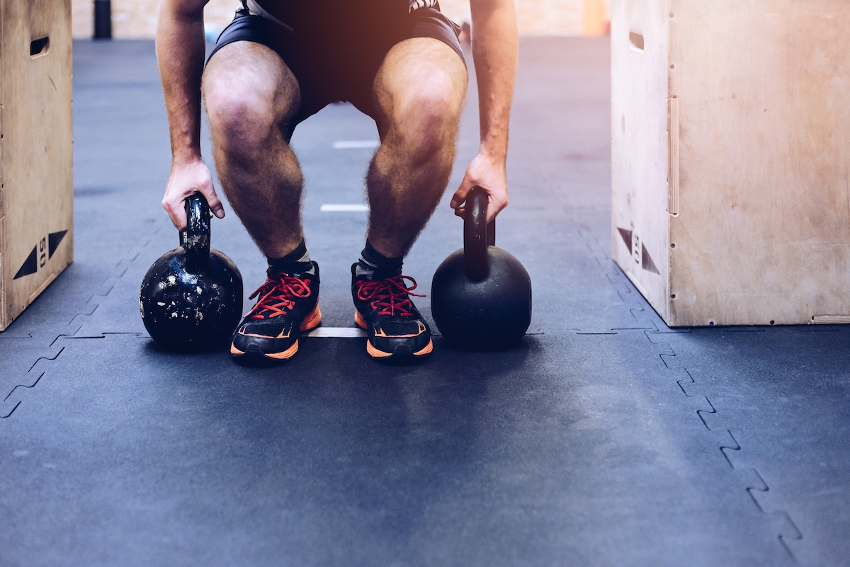 Man pulling kettlebells weights in the functional fitness gym. Kettle bell deadlift