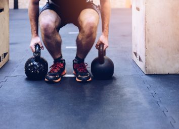 Man pulling kettlebells weights in the functional fitness gym. Kettle bell deadlift