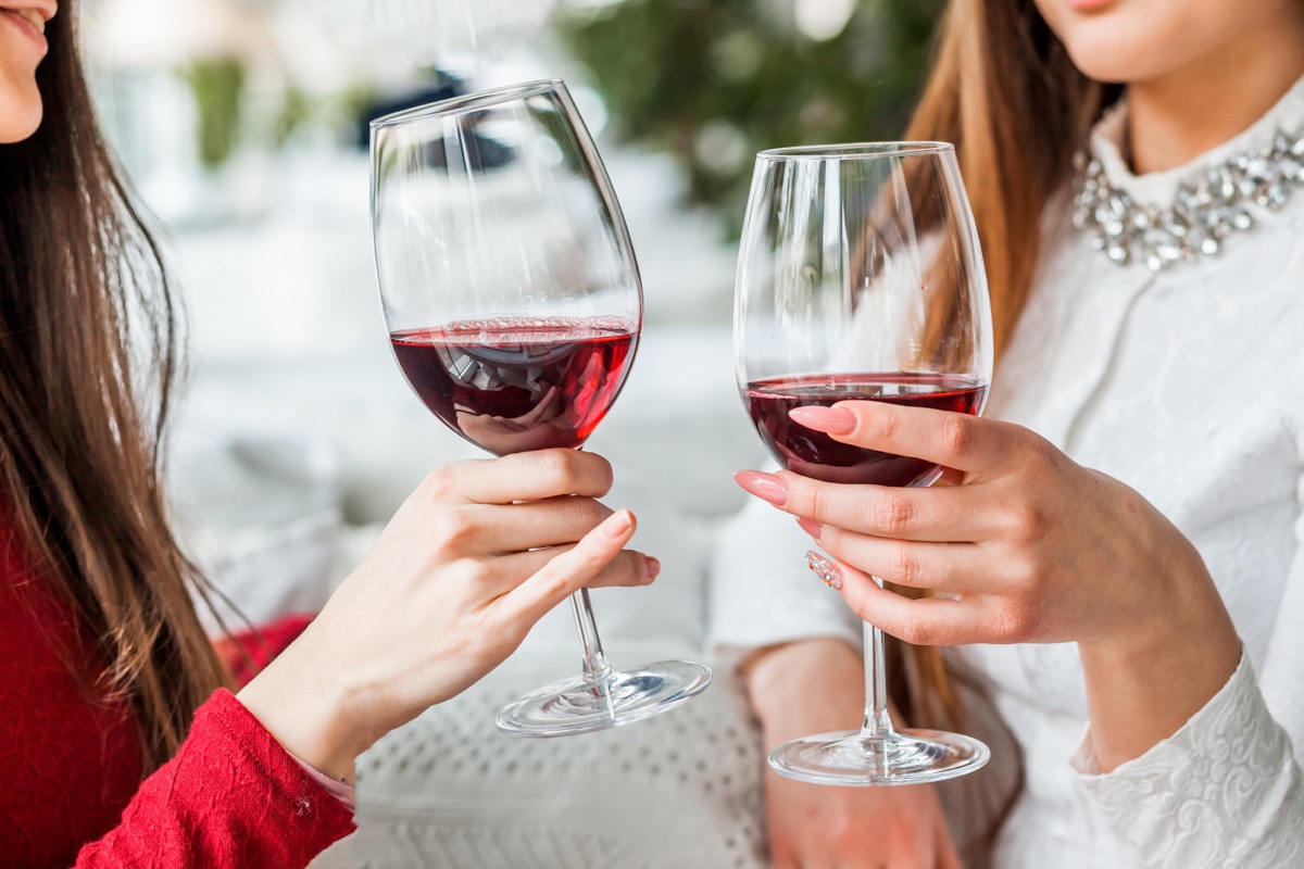 a woman in a red shirt and a woman in a white shirt toasting with glasses of wine