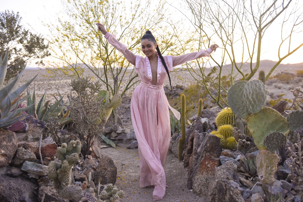 vanessa hudgens in pink jumpsuit outdoors with her arms raised