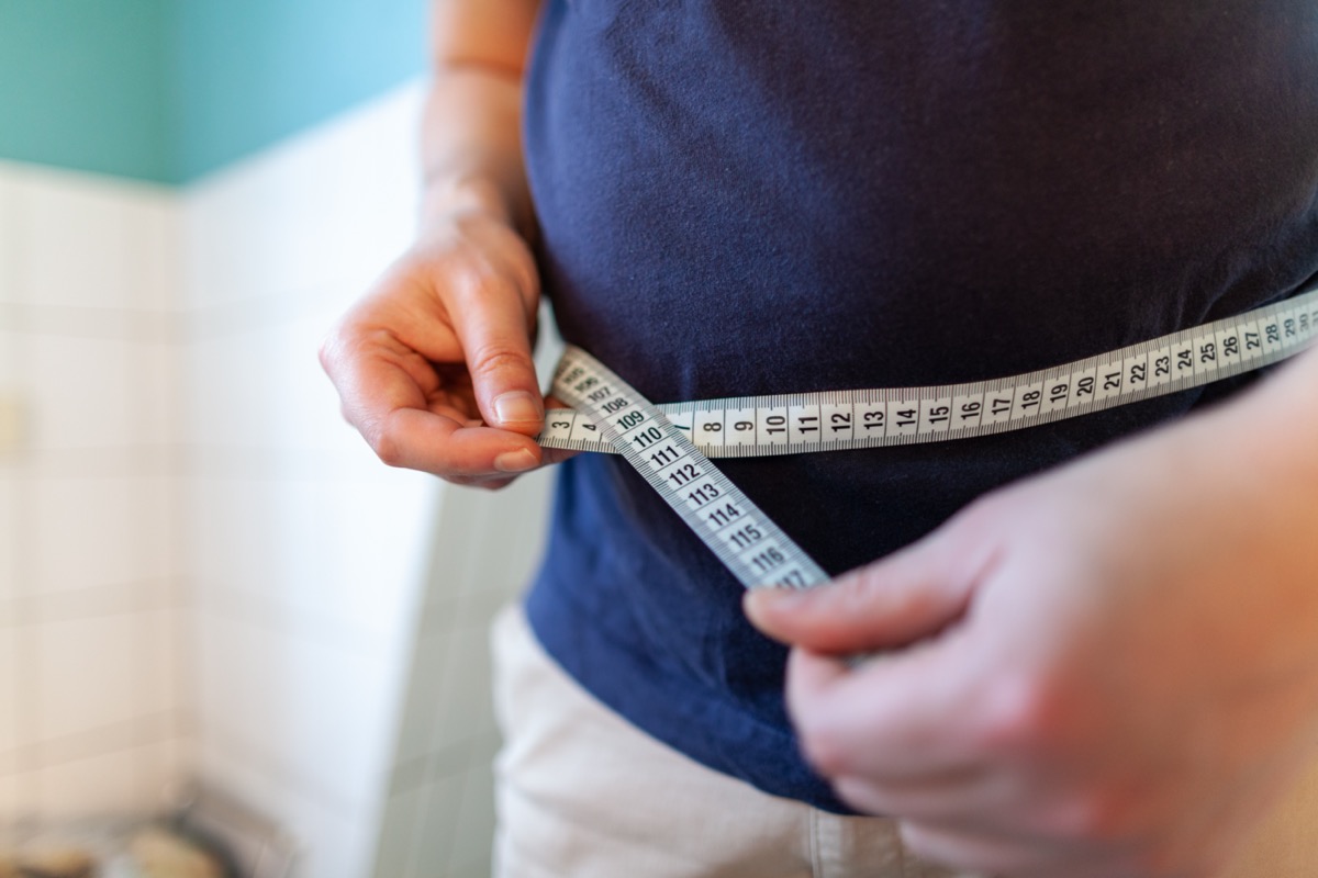 Man measures her abdomen with a measuring tape