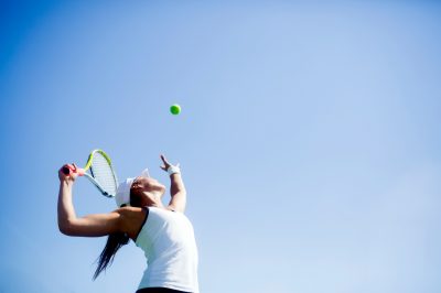 Beautiful female tennis player serving