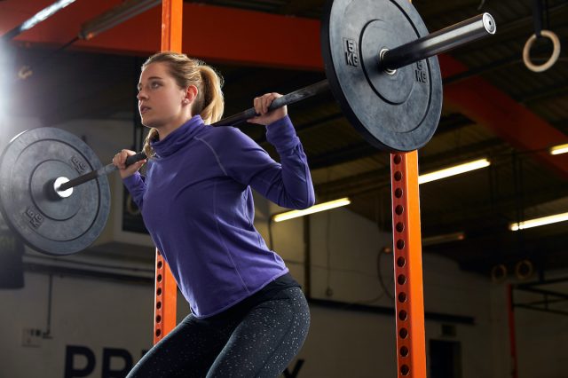 Woman lifting weights on barbell in gym
