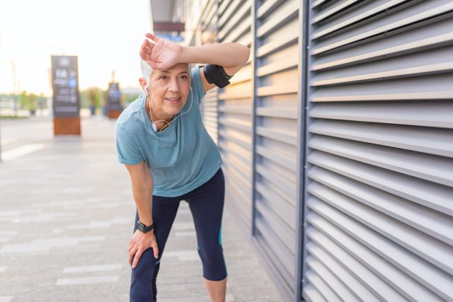 Müder älterer Mann nach dem Joggen.  Müder Senior ruht sich aus, nachdem er im Freien gelaufen ist.  Afrikanische Läuferin, die mit den Händen auf den Knien steht.  Fitness-Sportlerin, die sich nach einem intensiven Abendlauf ausruht