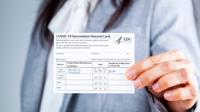 Woman is presenting COVID vaccination card.