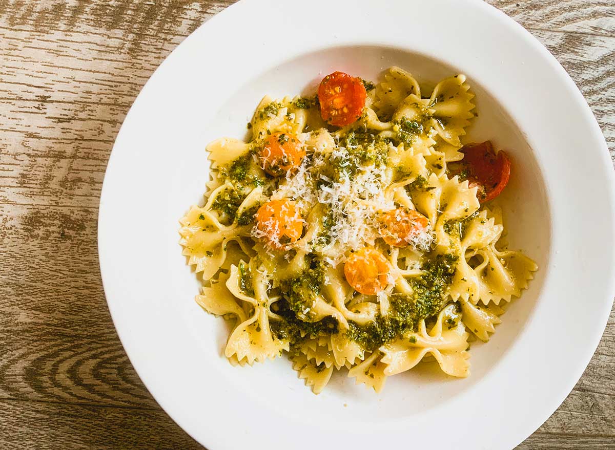 basil pesto mixed in with pasta and tomatoes and cheese