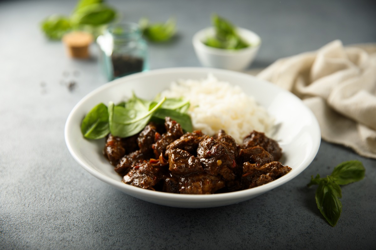 beef with rice and spinach in a white bowl