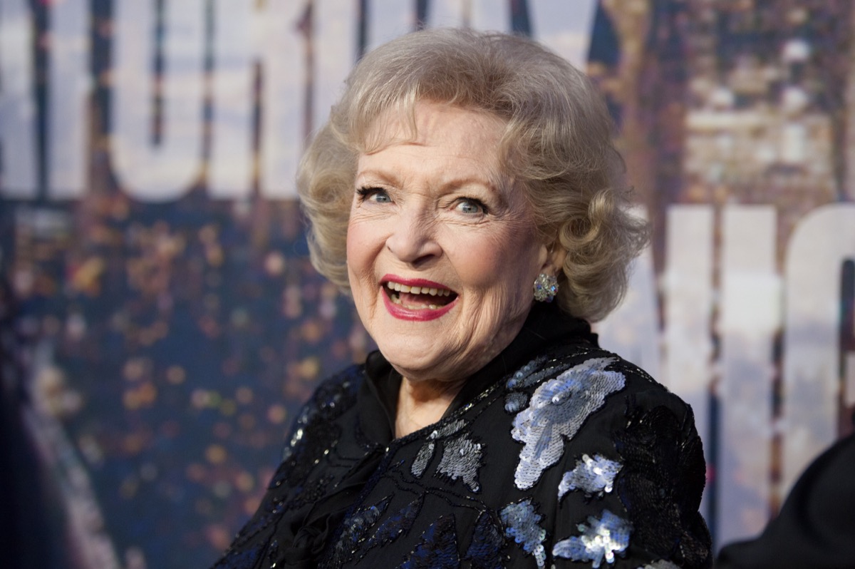 betty white laughing in black outfit on red carpet in front of snl step and repeat