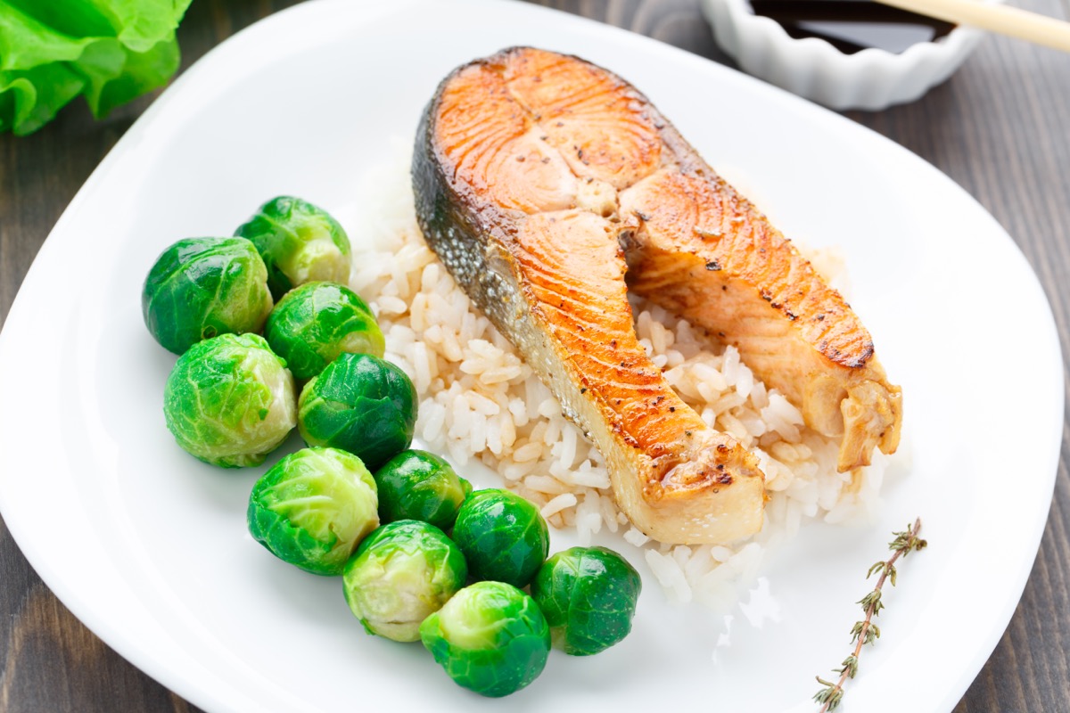 large salmon steak, brussels sprouts, and rice on white plate