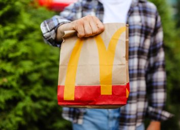 young man holding mcdonald's bag standing outdoors