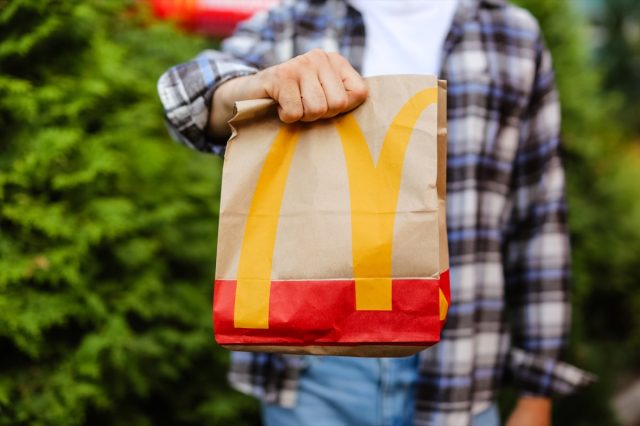 young man holding mcdonald's bag standing outdoors