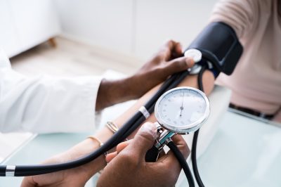 doctor taking patient's blood pressure with analog device