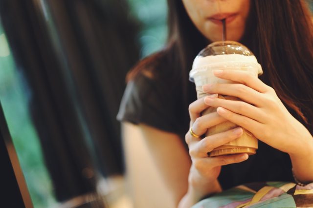 young woman drinking frozen coffee drink