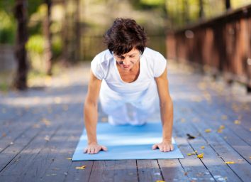 fit middle aged woman doing pushups outdoors