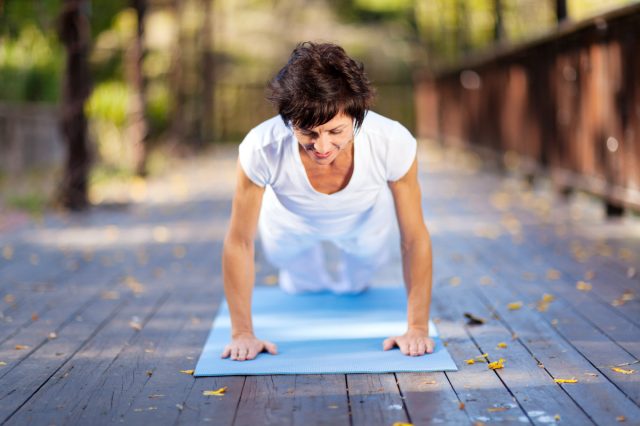 fit middle aged woman doing pushups outdoors