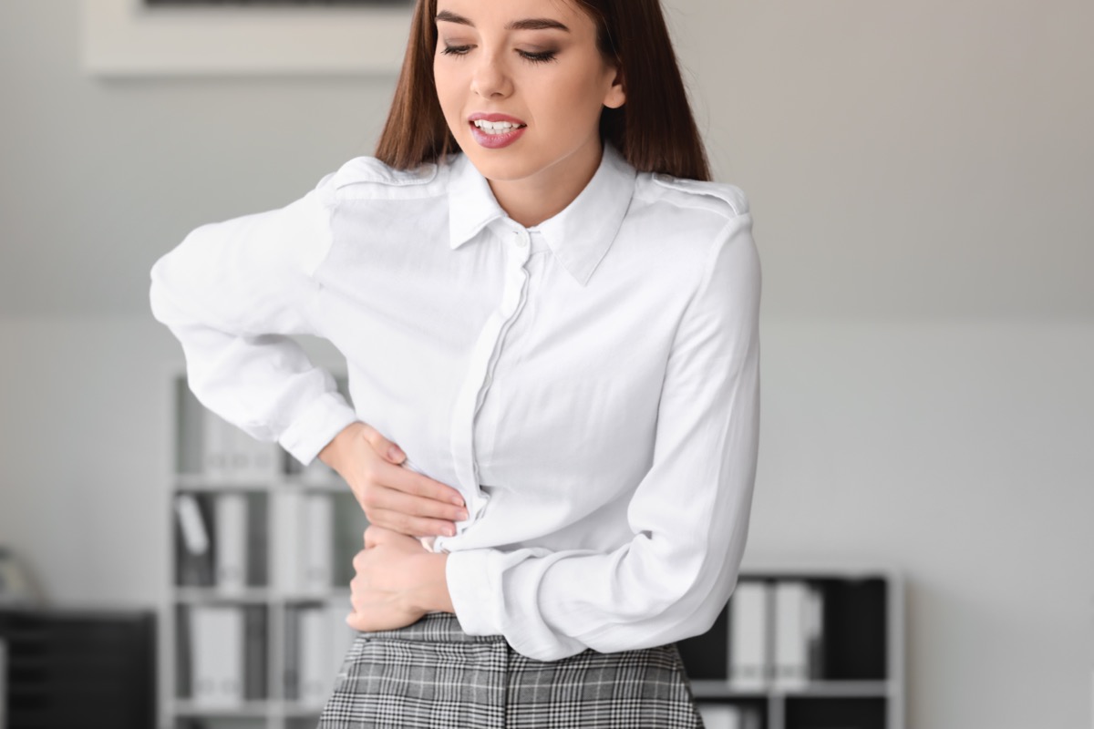 young woman in business attire experiencing liver pain