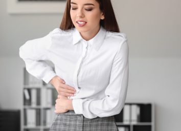 young woman in business attire experiencing liver pain