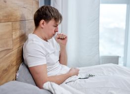Man lying on bed at home, high fever and coughing.