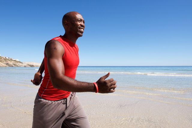 Bărbat de vârstă mijlocie în formă care se plimbă pe plajă într-o zi însorită