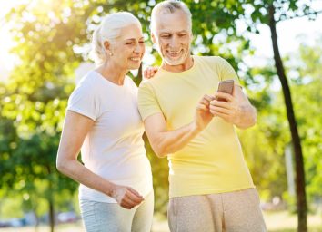 Happy mature couple looking at mobile phone in park.