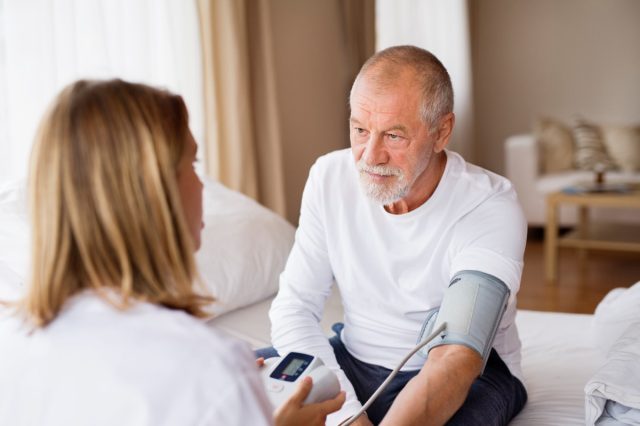 Health visitor and a senior man during home visit.