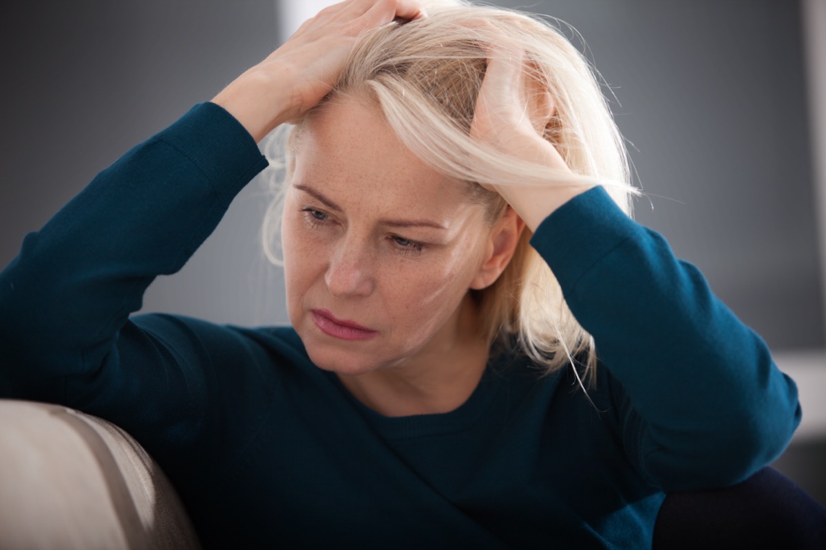 Sad middle aged woman sitting on a sofa in the living room