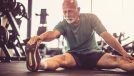 older man stretching in a gym