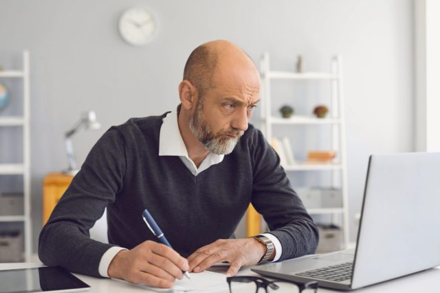 older man using laptop writing