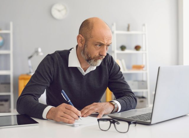 older man using laptop writing