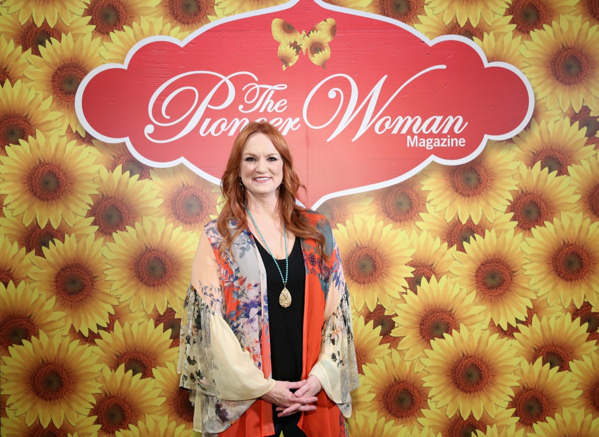 ree drummond in floral silk top standing against sunflower backdrop
