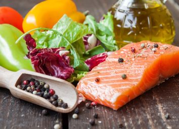 salmon, vegetables, and olive oil on wooden backdrop