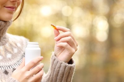 young woman in fair isle turtleneck taking supplement while standing outdoors