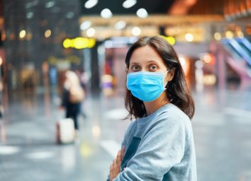 Traveler woman in virus protection face mask in international airport.