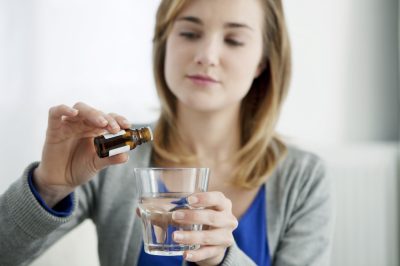 Woman pouring oils to glass.