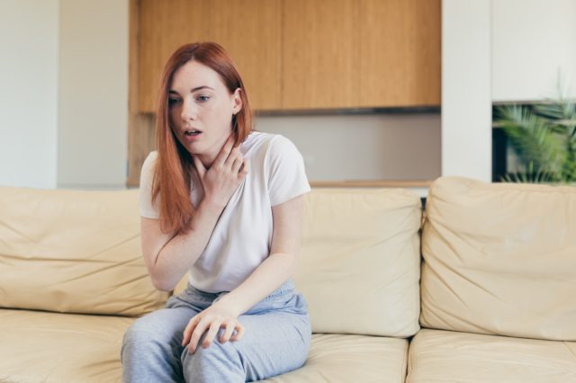 Mujer que sufre ansiedad sentada en un sofá.
