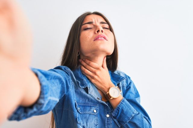 Woman touching painful neck.