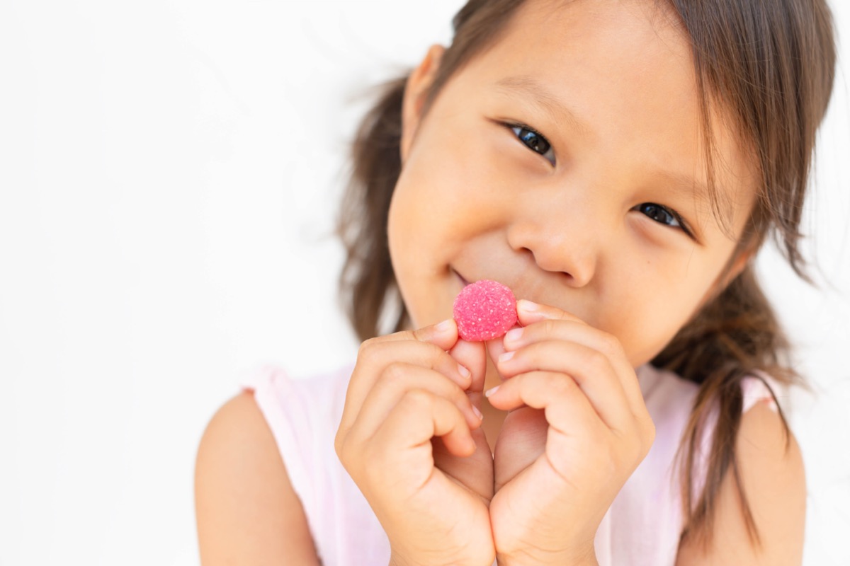 A happy kid holding a vitamin.