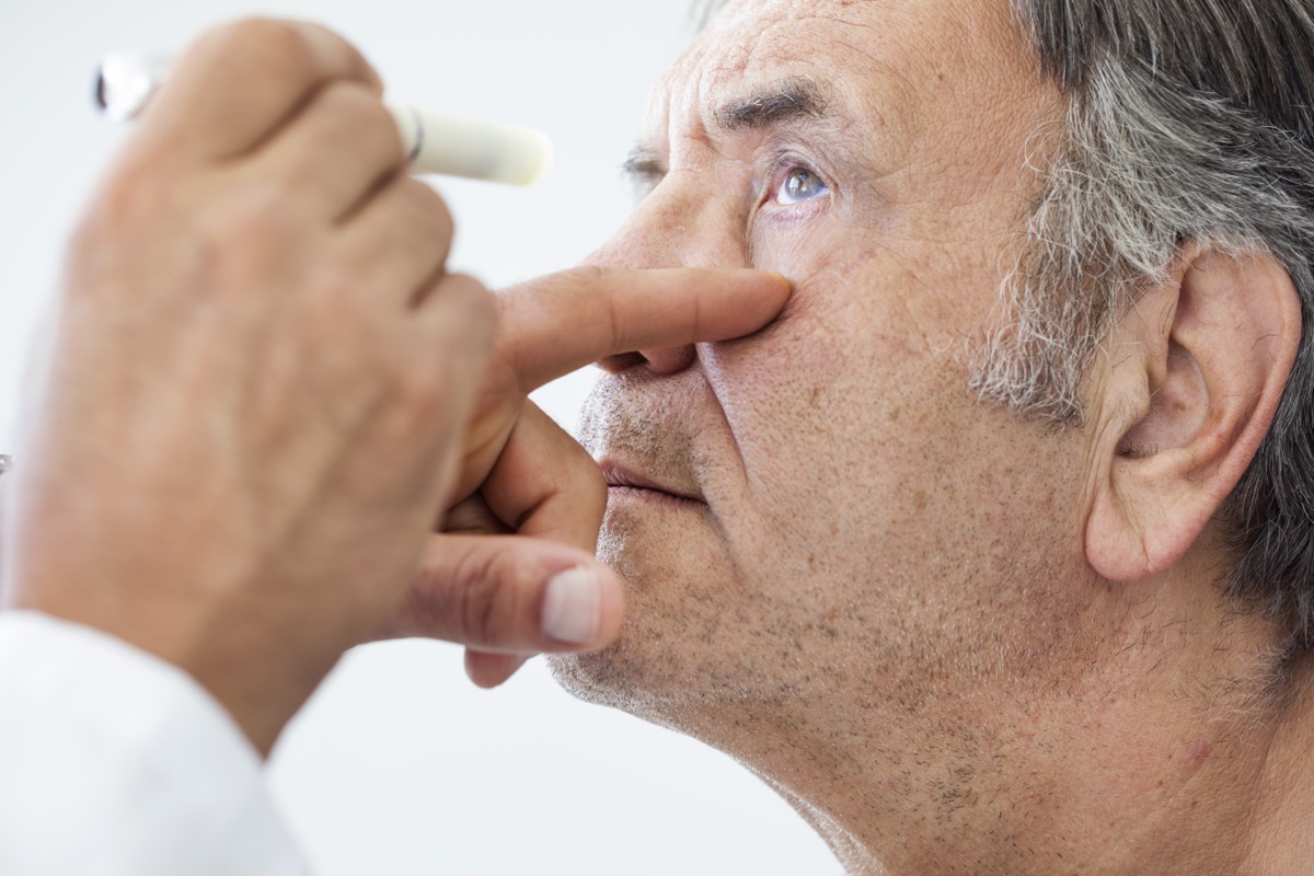 El anciano hace el examen de los ojos.