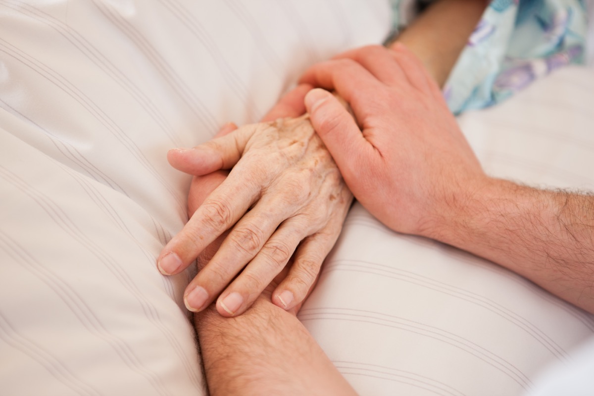 person holding hands with someone in hospital bed