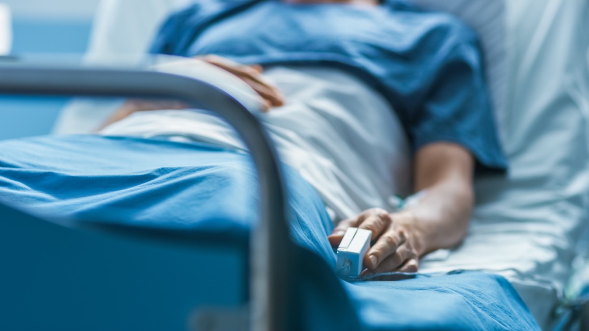 person in hospital bed with pulse ox on finger