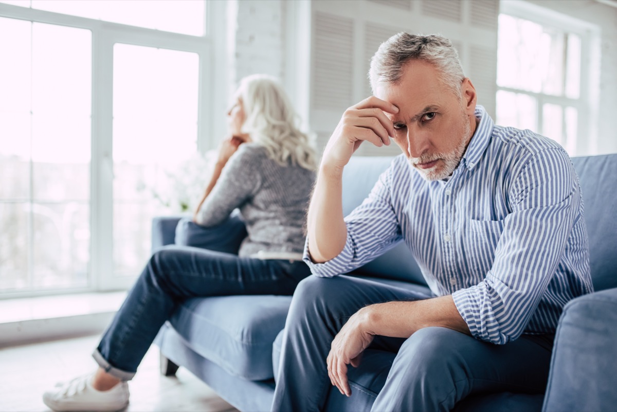 Mature couple sitting on sofa together and looking to opposite sides.